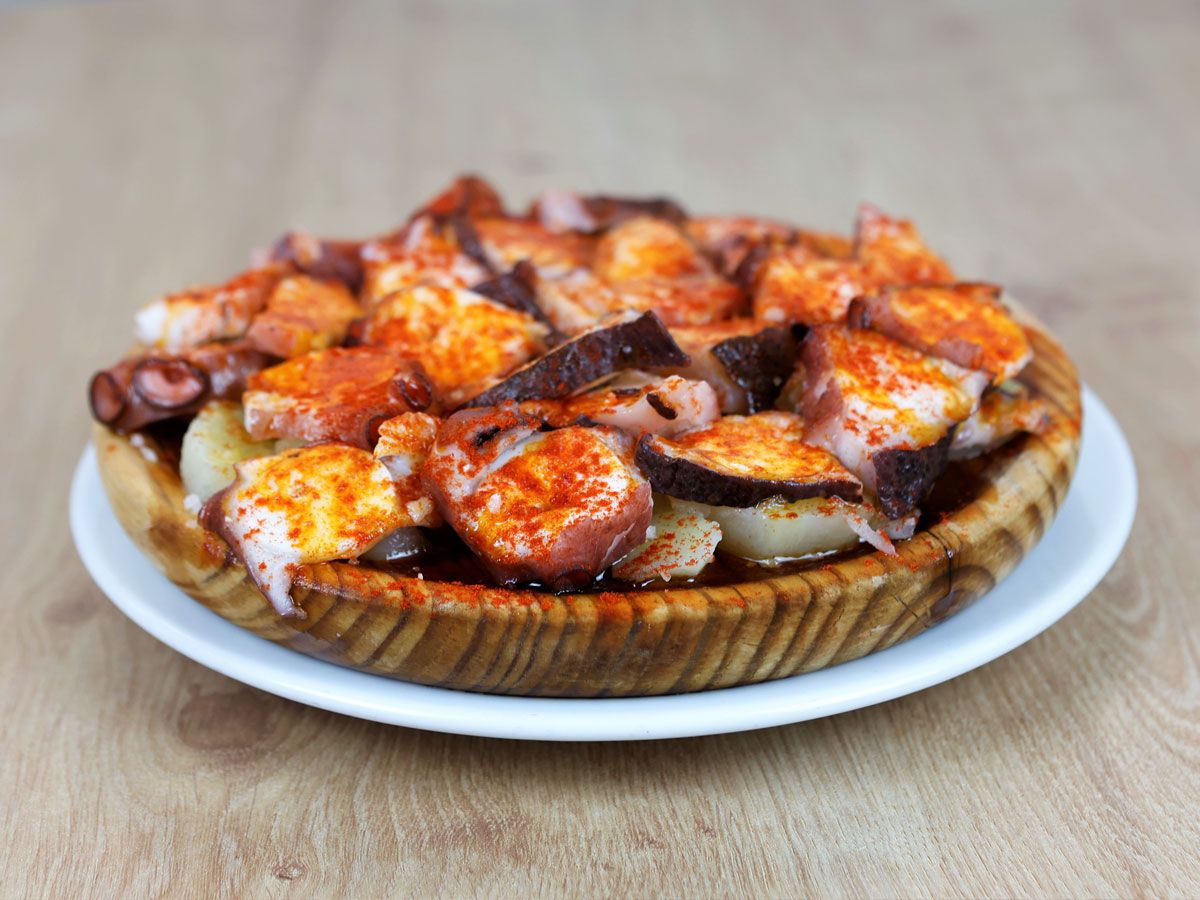 Pulpo á feira con pimentón y aceite de oliva, servido en plato de madera
