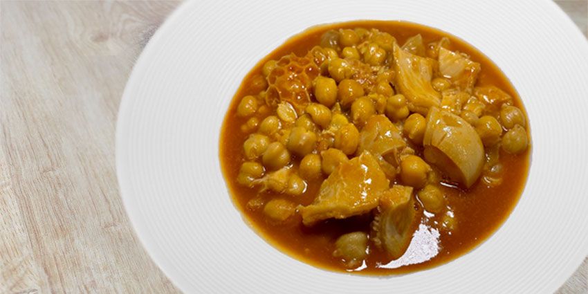 Callos guisados con garbanzos en salsa roja servidos en un plato hondo blanco