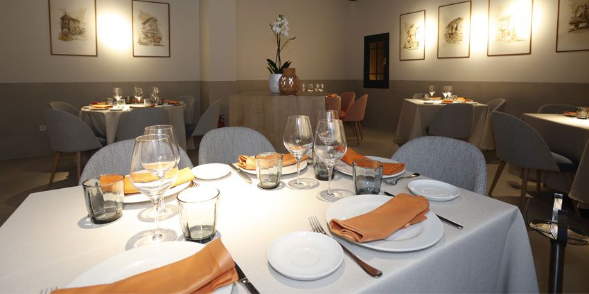 Comedor de Flor de Galicia con mesas vestidas de blanco y cuadros de Galicia en las paredes