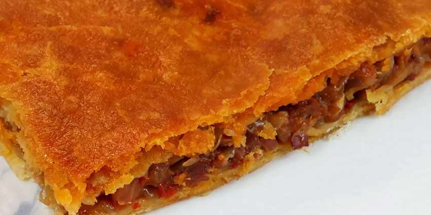 Porción de empanada gallega con masa dorada y relleno