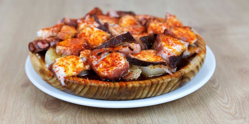 Pulpo a la gallega con pimentón y cachelos sobre un plato de madera