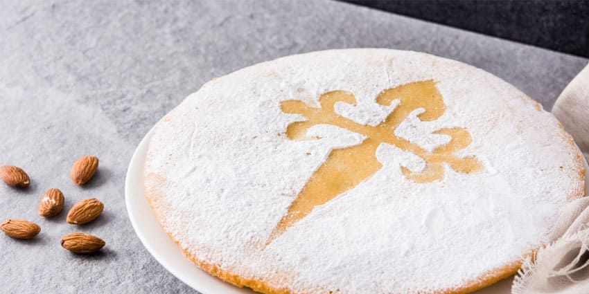 Tarta de Santiago con la cruz de Santiago dibujada en azúcar glas y unas almendras al lado