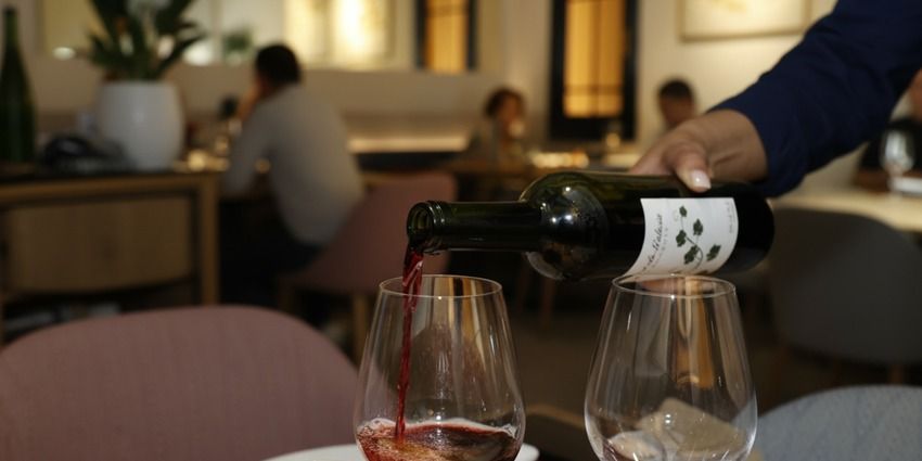Camarero sirviendo vino tinto en una copa sobre una mesa del comedor de Flor de Galicia