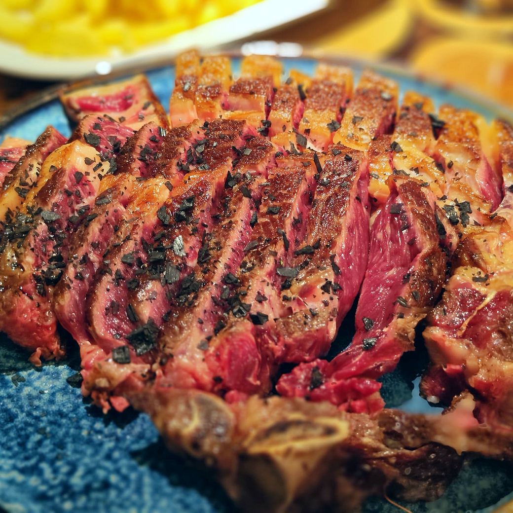 Chuletón de vaca gallega trinchado, hecho a la parrilla y servido en plato de barro